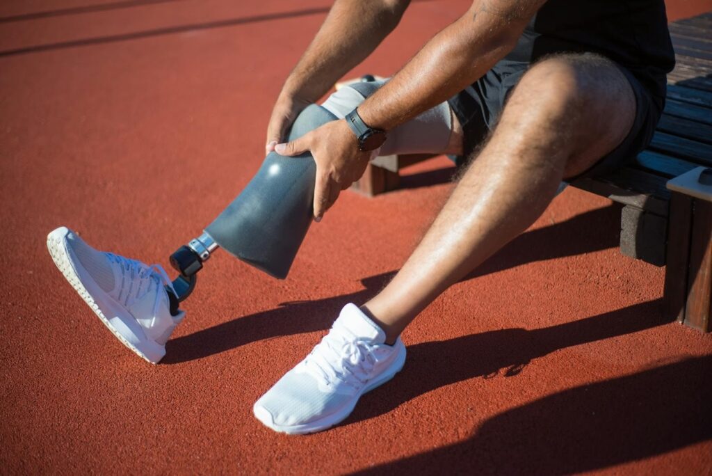 Un coureur équipé d’une prothèse de jambe la replace sur une piste d’athlétisme.